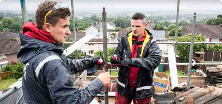 An experienced builder demonstrates skills to a younger apprentice on a domestic building site